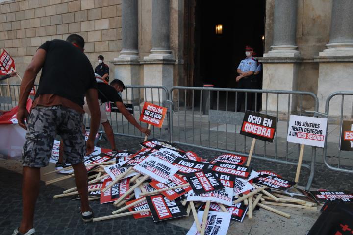 Pla tancat de dos treballadors de l'oci nocturn deixant les seves pancartes de protesta davant el Palau de la Generalitat. ACN