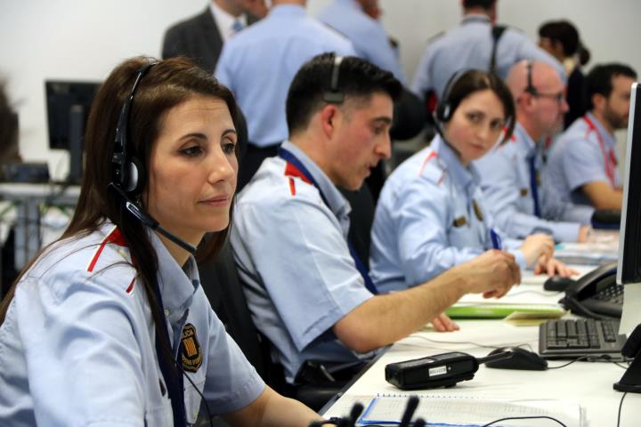 Primer pla d'una agent dels Mossos d'Esquadra, amb auriculars i micròfon, atenent incidents policials a la sala de comandament del 112 de Reus. ACN