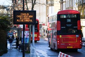 Un bus de Londres passa pel costat d'un cartell que alerta de l'alta incidència de la covid-19 a la capital britànica. Reuters