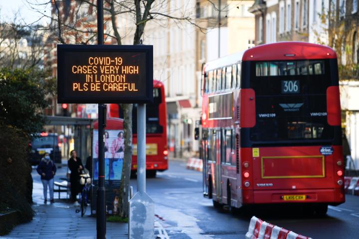 Un bus de Londres passa pel costat d'un cartell que alerta de l'alta incidència de la covid-19 a la capital britànica. Reuters