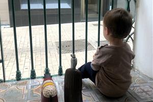 Un nen mira per la finestra de casa, durant el confinament. ACN