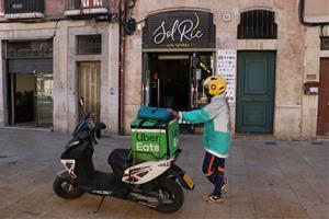 Un repartidor a domicili esperant la comanda d'un restaurant que ha obert en el primer dia de restriccions. ACN / Mar Rovira