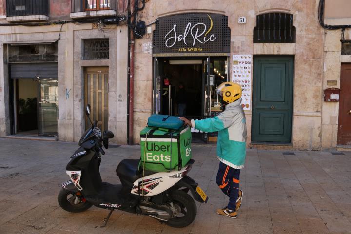 Un repartidor a domicili esperant la comanda d'un restaurant que ha obert en el primer dia de restriccions. ACN / Mar Rovira