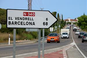 Un rètol de trànsit en primer terme a l'N-340 a Roda de Berà, amb els quilòmetres que separen Roda de Berà del Vendrell i Barcelona. ACN