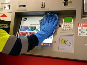 Un treballador de TMB neteja una màquina de venda de bitllets. TMB