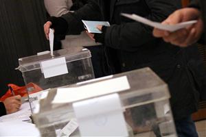 Una mà diposita un vot en una urna, amb una segona urna en primer pla, el 21 de desembre de 2017. ACN
