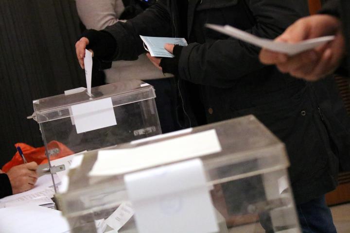 Una mà diposita un vot en una urna, amb una segona urna en primer pla, el 21 de desembre de 2017. ACN