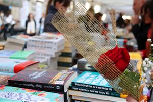 Una parada de llibres de Sant Jordi amb una rosa en primer pla. Imatge del 23 d'abril de 2019. ACN