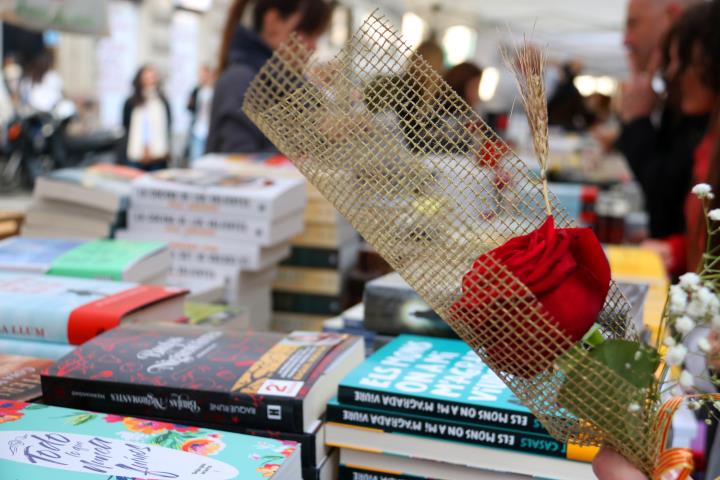 Una parada de llibres de Sant Jordi amb una rosa en primer pla. Imatge del 23 d'abril de 2019. ACN
