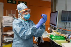 Una professional sanitària es posa guants abans d'entrar en una habitació ocupada per un pacient amb coronavirus a l'Hospital Clínic