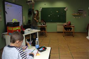 Una professora amb mascareta i utilitzant el projector de l'aula i un grup d'alumnes distanciats entre ells a l'escola Jordi Pere Cerdà de Sallagosa. 