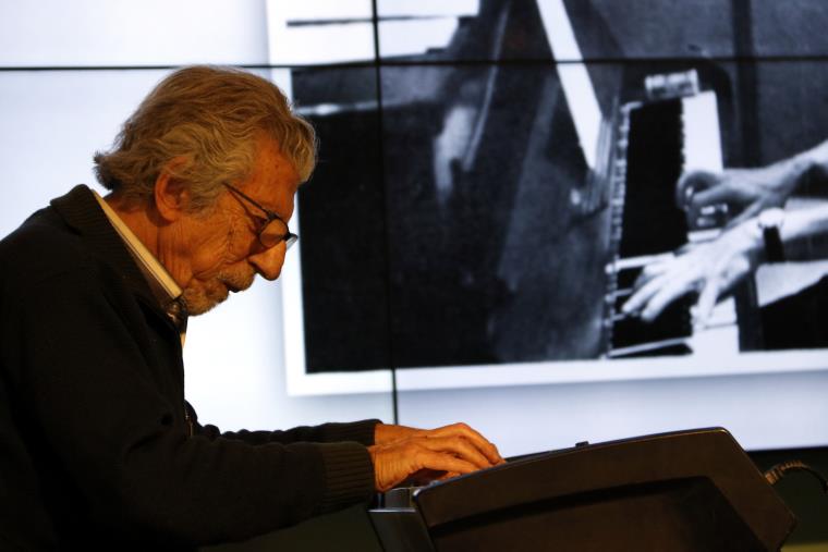Detall de Francesc Burrull tocant el piano amb una foto seva antiga. ACN