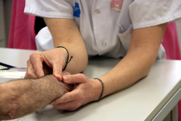 Pla detall de les mans d'una infermera prenent el pols a un pacient. ACN