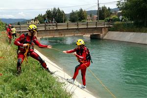 Pla general de dos bombers fent pràctiques de rescat aquàtic al canal de Gavet. Un bombers estira amb una coda a un altre que simulava haver caigut. A