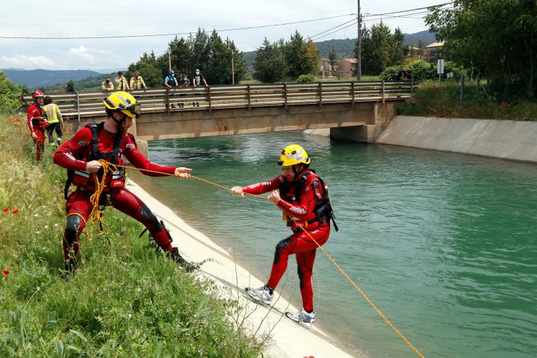 Pla general de dos bombers fent pràctiques de rescat aquàtic al canal de Gavet. Un bombers estira amb una coda a un altre que simulava haver caigut. A