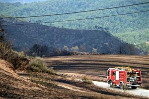 Pla general d'un vehicle dels Bombers enmig d'un paisatge cremat, a Bellprat. Imatge del 26 de juliol del 2021. ACN