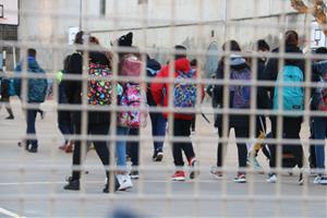 Pla mitjà de diversos nens i nenes entrant a l'escola. ACN