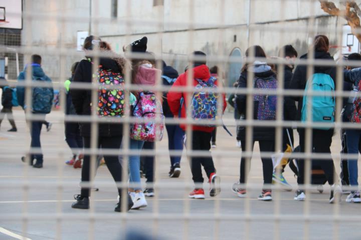 Pla mitjà de diversos nens i nenes entrant a l'escola. ACN