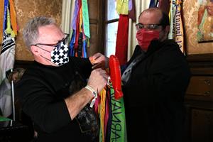 Pla mitjà dels organitzadors del Carnaval de Vilanova posant les llaçades simbòliques a les banderes de les Comparses
