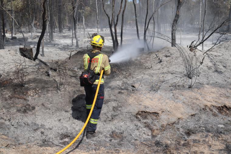 Pla mitjà d'un bomber remullant una de les zones cremades a l'incendi de Ventalló aquest diumenge 25 de juliol de 2021. ACN