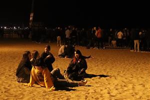 Pla obert d'un grup d'amics asseguts a la platja de la Barceloneta. ACN