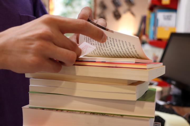 Primer pla d'un llibreter etiquetant una pila de llibres la vigília del Sant Jordi d'estiu. ACN