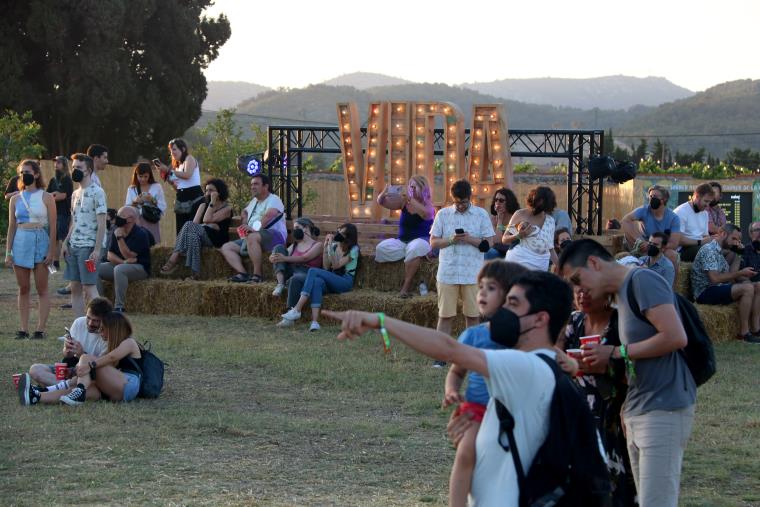 Públic del festival Vida a la Masia d'en Cabanyes amb les lletres de fons, l'1 de juliol del 2021. ACN