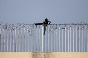 Un menor immigrant no acompanyat intenta saltar una tanca, a Ceuta. ACN / Pedro Armestre