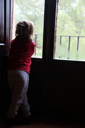 Un nen observa les volves de neu des de la finestra de casa. Imatge del 25 de març del 2020. ACN