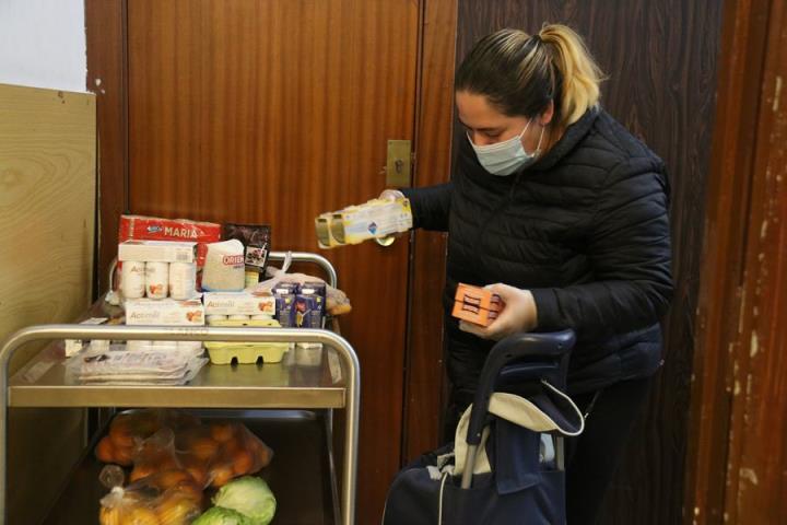 Una dona omple un carro de menjar a un punt de distribució d'aliments de Cáritas. ACN