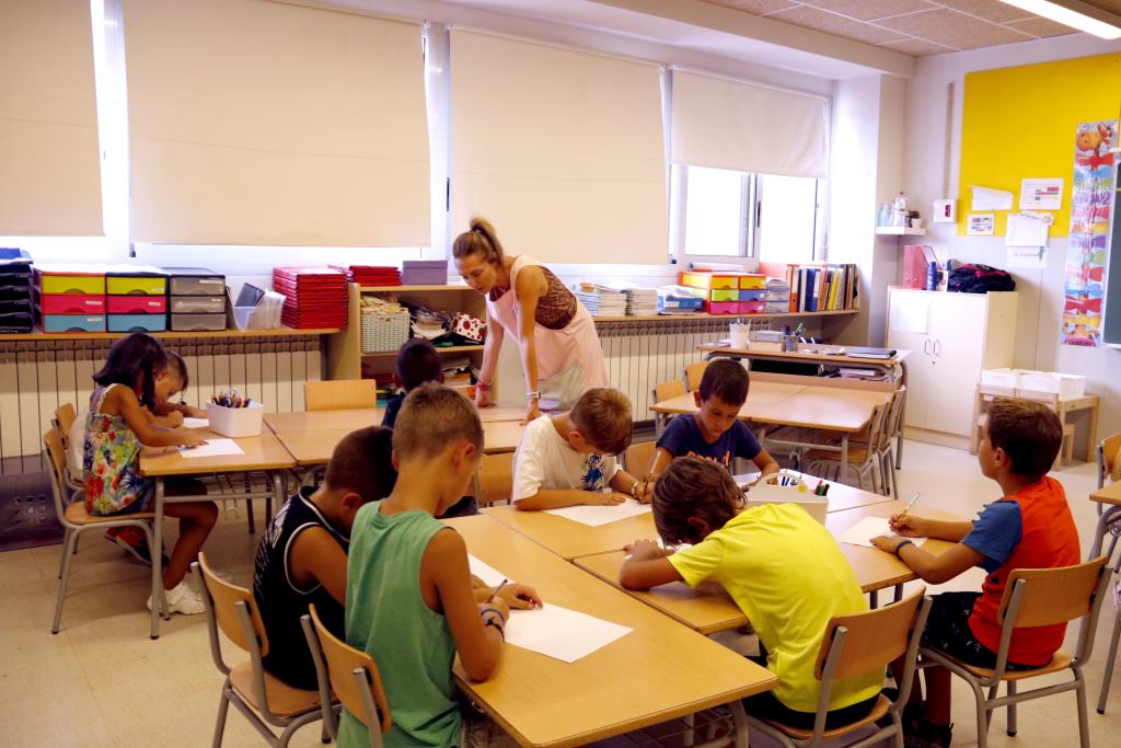 Alumnes de segon de primària durant l'hora de lleure educatiu, amb una de les monitores. ACN / Laura Cortés