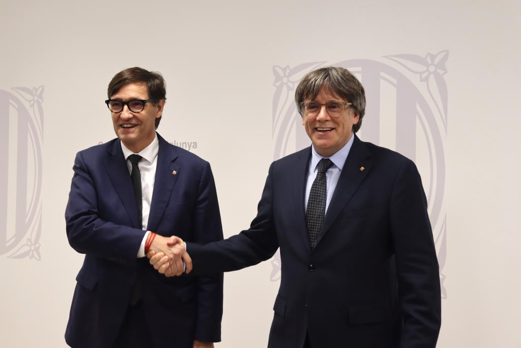 El president Salvador Illa i l'expresident Carles Puigdemont encaixen les mans abans de reunir-se a Brussel·les . ACN / Maria Rodríguez