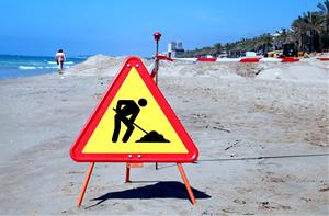 Senyal d'obres a la platja de Calafell per indicar que s'està treballant en el traspàs de sorra. ACN / Mar Rovira