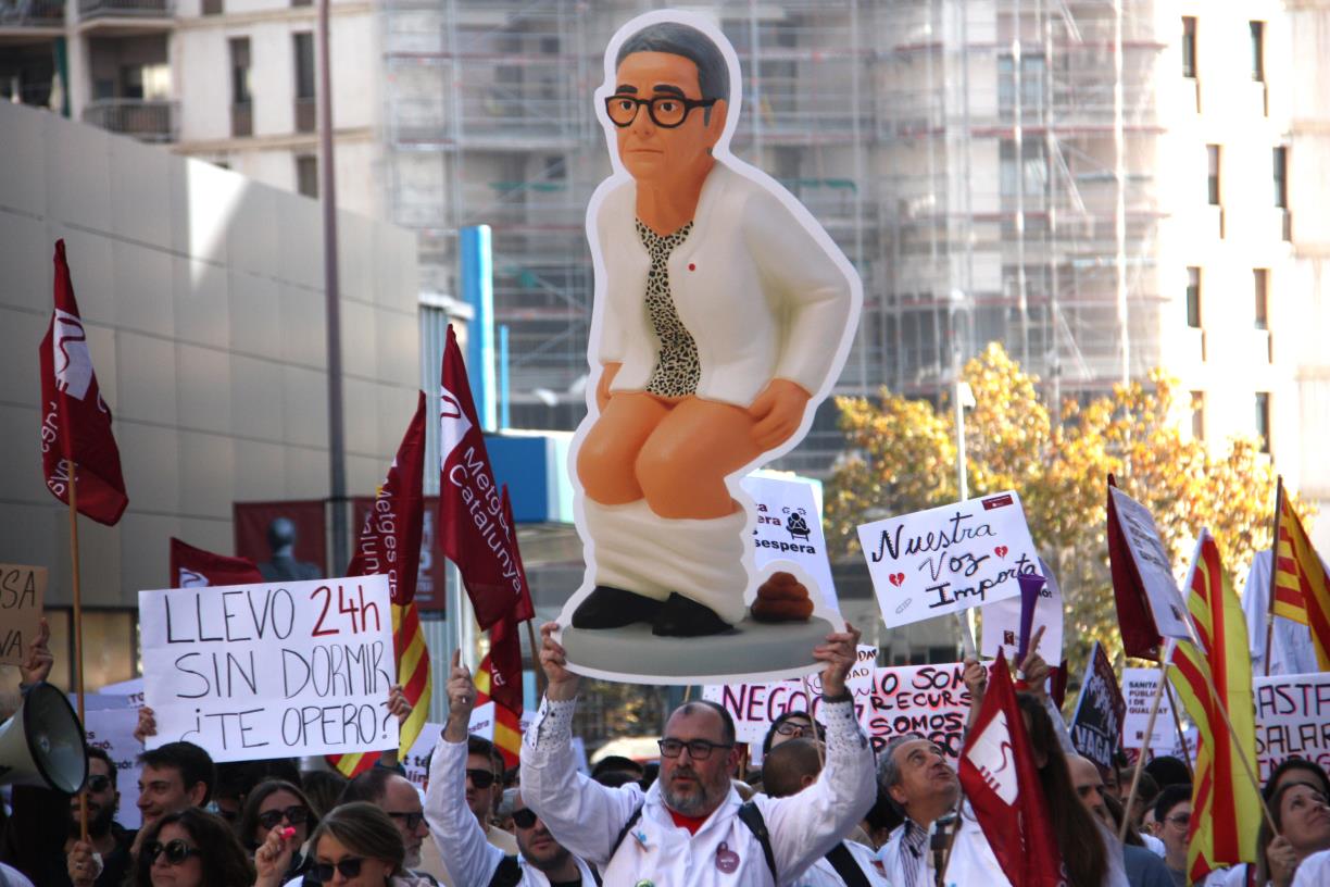 Un assistent a la manifestació alça la figura de la consellera de salut de la Generalitat, Olga Pané. ACN / Clàudia Corbella