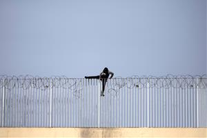 Un menor immigrant no acompanyat intenta saltar una tanca, a Ceuta. ACN / Pedro Armestre 