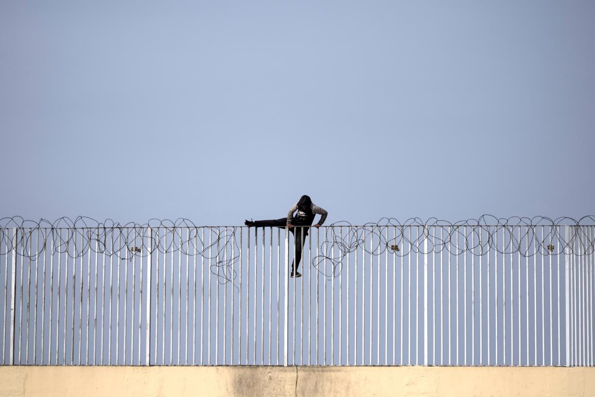 Un menor immigrant no acompanyat intenta saltar una tanca, a Ceuta. ACN / Pedro Armestre 