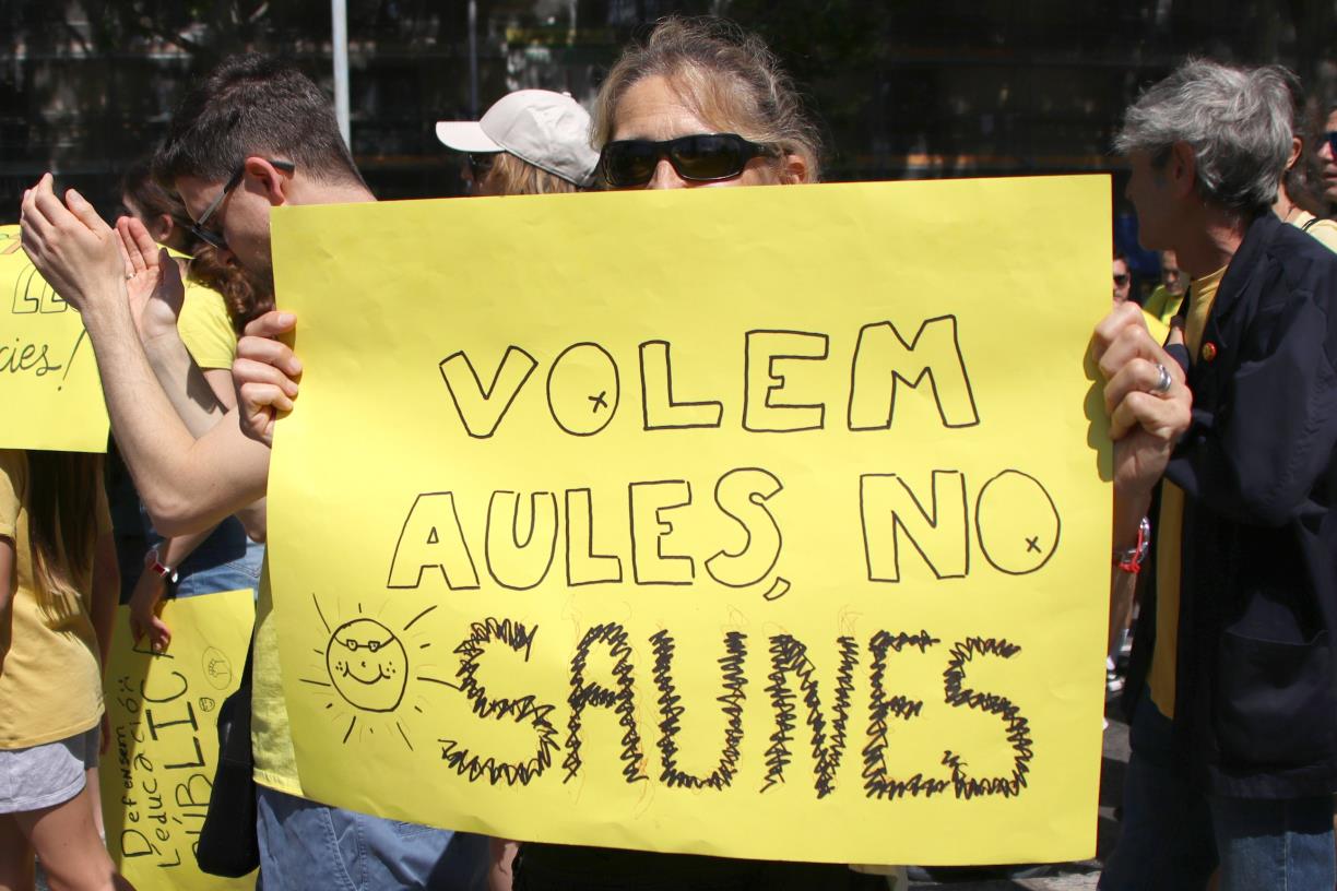 Una dona amb un cartell en contra de la calor a les aules . ACN / Blanca Blay